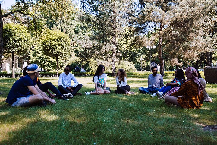 Zdjęcie grupy młodych ludzi siedzących w półokręgu na trawie